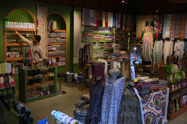 A vendor arranges products inside a shop at the empty Al Seef market, next to the historic Al Fahidi neighborhood along Dubai Creek, one of the main tourist areas of Dubai, United Arab Emirates, Friday, March 13, 2026, as tourism slows amid regional tensions linked to the Iran war. (AP Photo/Fatima Shbair)