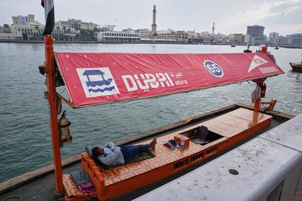 An abra driver sleeps in his boat along Dubai Creek in Dubai, United Arab Emirates, Tuesday, March 10, 2026. (AP Photo/Fatima Shbair)