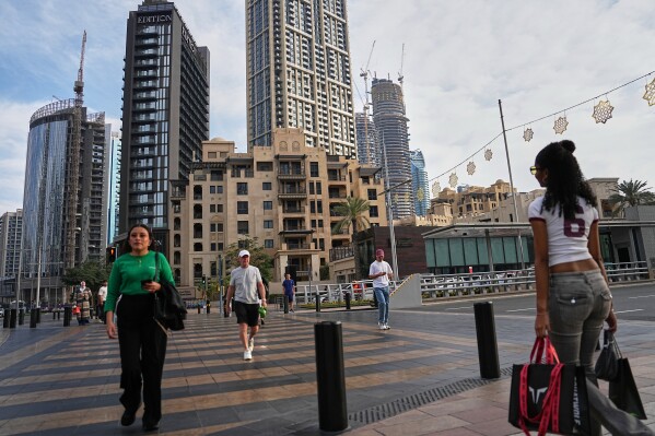 People cross a street in downtown Dubai, United Arab Emirates, Saturday, March 7, 2026. (AP Photo/ Fatima Shbair)