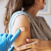 A woman's arm gets an adhesive bandage after she was immunized.