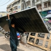 A labourer walks through Karachi with a solar panel