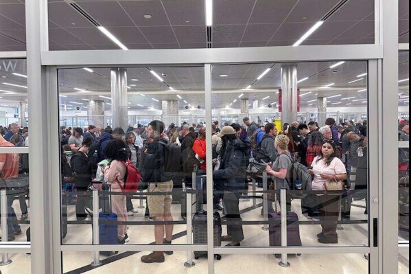 Travelers wait in line at a security checkpoint at Hartsfield-Jackson Atlanta International Airport on Monday, March 16, 2026. (AP Photo/Emilie Megnien)