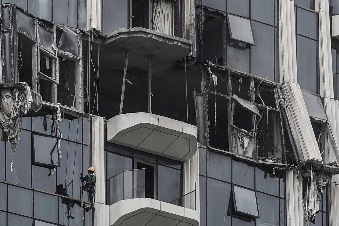 A worker assesses the damage after a building was hit by a reported drone strike in Dubai on March 12.