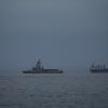A United Arab Emirates navy vessel patrols next to cargo ships and oil tankers in the Strait of Hormuz, as seen from Khor Fakkan, United Arab Emirates, March 11.