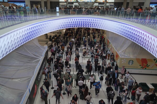 Travelers line up at a TSA checkpoint at George Bush Intercontinental Airport in Houston, Tuesday, March 24, 2026. (AP Photo/Lekan Oyekanmi)