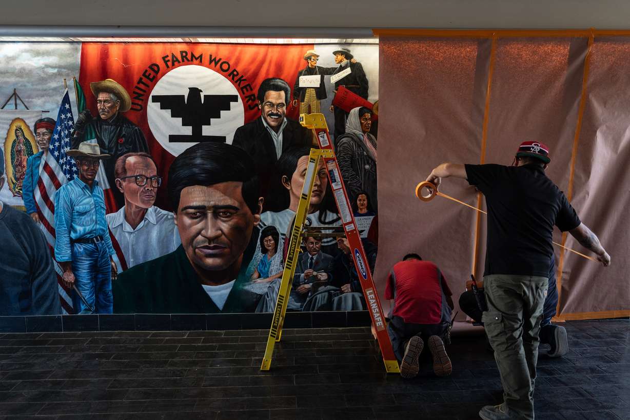 Workers cover a mural by Emigdio Vasquez featuring Cesar Chavez and other figures at Santa Ana College in Santa Ana, California on Thursday.
