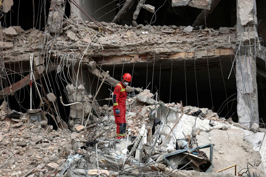 An Iranian firefighter walks on the rubble of a destroyed residential building in Tehran, Iran, on March 23, 2026.