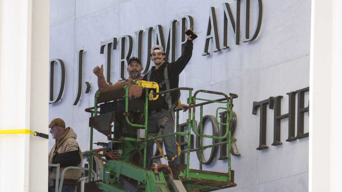 Workers react to the media after updating signage outside the Kennedy Center on Dec. 19, 2025, in Washington, D.C.