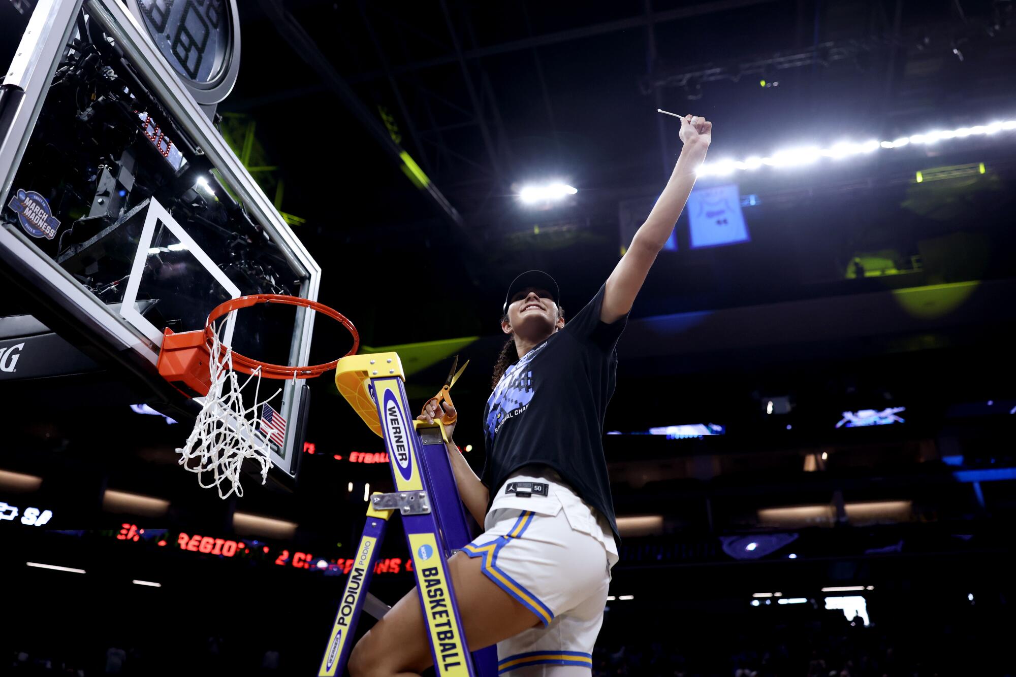 UCLA center Lauren Betts holds up a piece of the net after the Bruins' win over Duke.