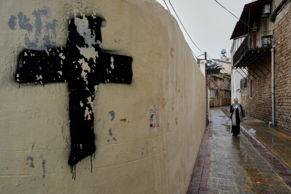 A woman walks in one of the Christian alleys on her way to attend Palm Sunday Mass at Saint Thomas Cathedral, in the southern port city of Tyre, south Lebanon, Sunday, March 29, 2026. (AP Photo/Hussein Malla)