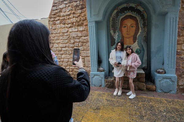 A Christian woman takes pictures of her daughters outside a church, as they celebrate Palm Sunday in the southern port city of Tyre, south Lebanon, Sunday, March 29, 2026. (AP Photo/Hussein Malla)