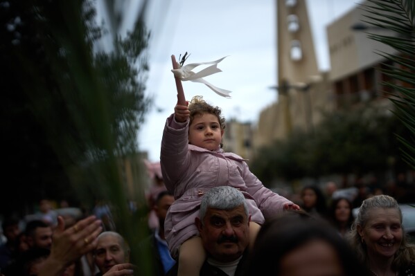 Catholic worshipers carry their children on their shoulders as they march in a procession during a Palm Sunday Mass in Beirut, Lebanon, Sunday, March 29, 2026. (AP Photo/Emilio Morenatti)