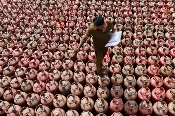 A worker inspects liquefied petroleum gas cylinders, arranged for customer delivery at a distribution centre on the outskirts of Amritsar, India, Friday, March 13, 2026. (AP Photo/Prabhjot Gill)