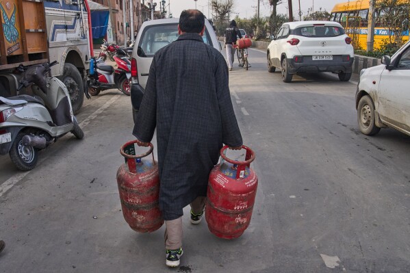A Kashmiri man carries household cylinders of liquefied natural gas after collecting them from an authorized dealer in Srinagar, Indian controlled Kashmir, Saturday, March 14, 2026. (AP Photo/Dar Yasin)