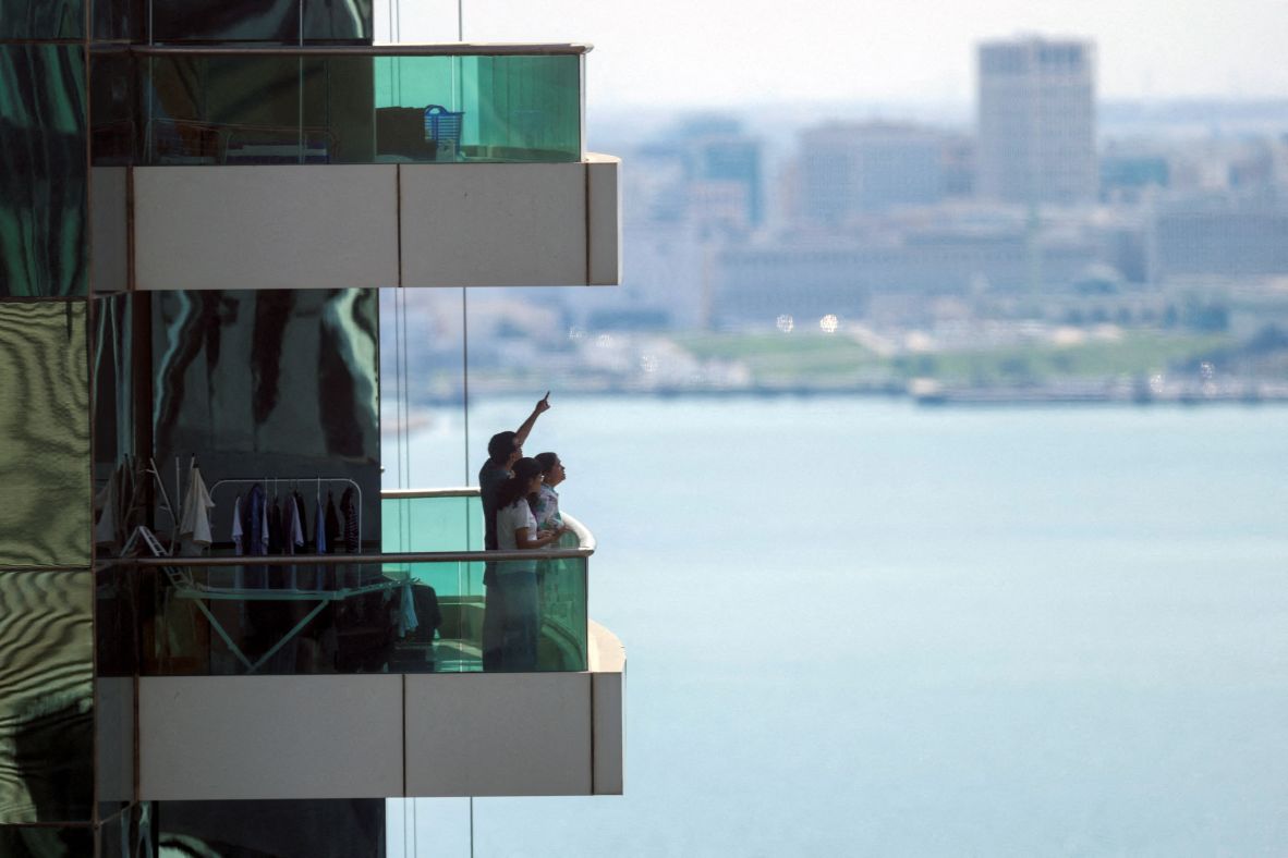 People in Doha, Qatar, watch from their balcony following explosions on February 28. Qatar's defense ministry said it had downed missiles targeting the country.