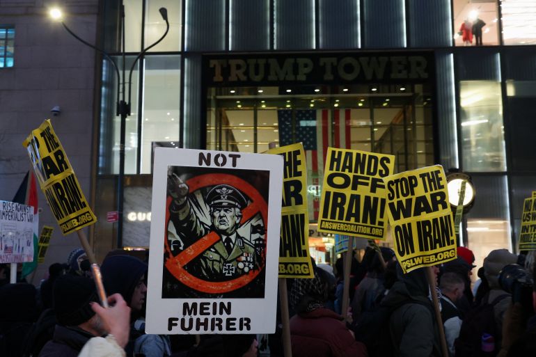 Demonstrators display signs as they march past Trump Tower, while taking part in a protest against the U.S.-Israel conflict with Iran
