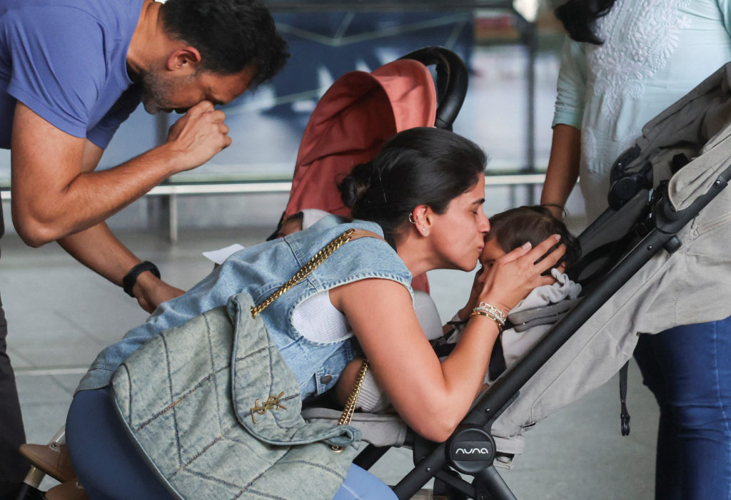 A mother kisses her child after they returned from Dubai amid the U.S.-Israel conflict with Iran, at the Chhatrapati Shiva...