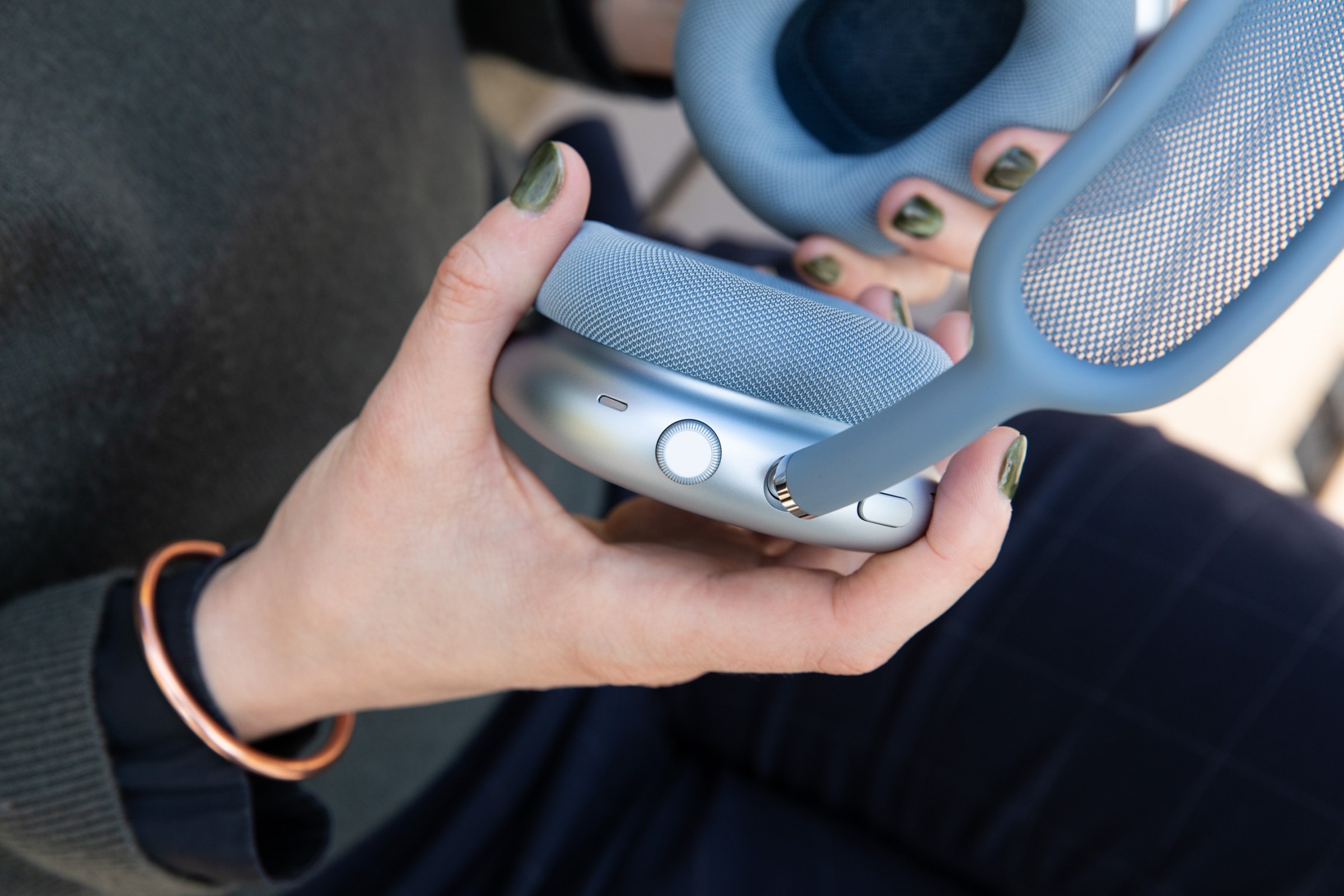 Hands holding the Apple AirPods Max 2 to show a closeup of the button and digital crown.