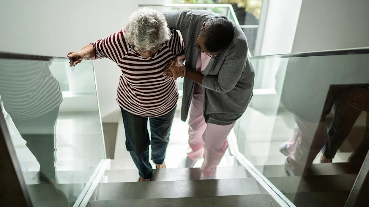 Nurse helping a senior woman walking up the stairs