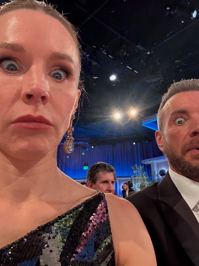 Kristen Bell and Dax Shepard at a formal event, showing surprised expressions under bright studio lights.