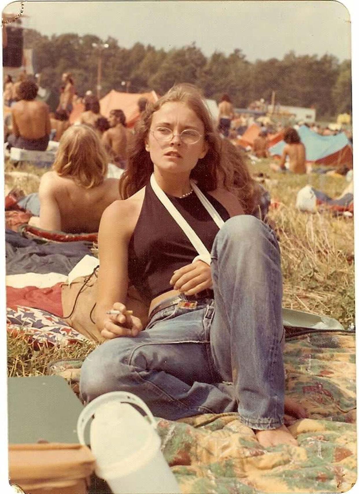 A young woman with her arm in a sling laying in a field at a concert -