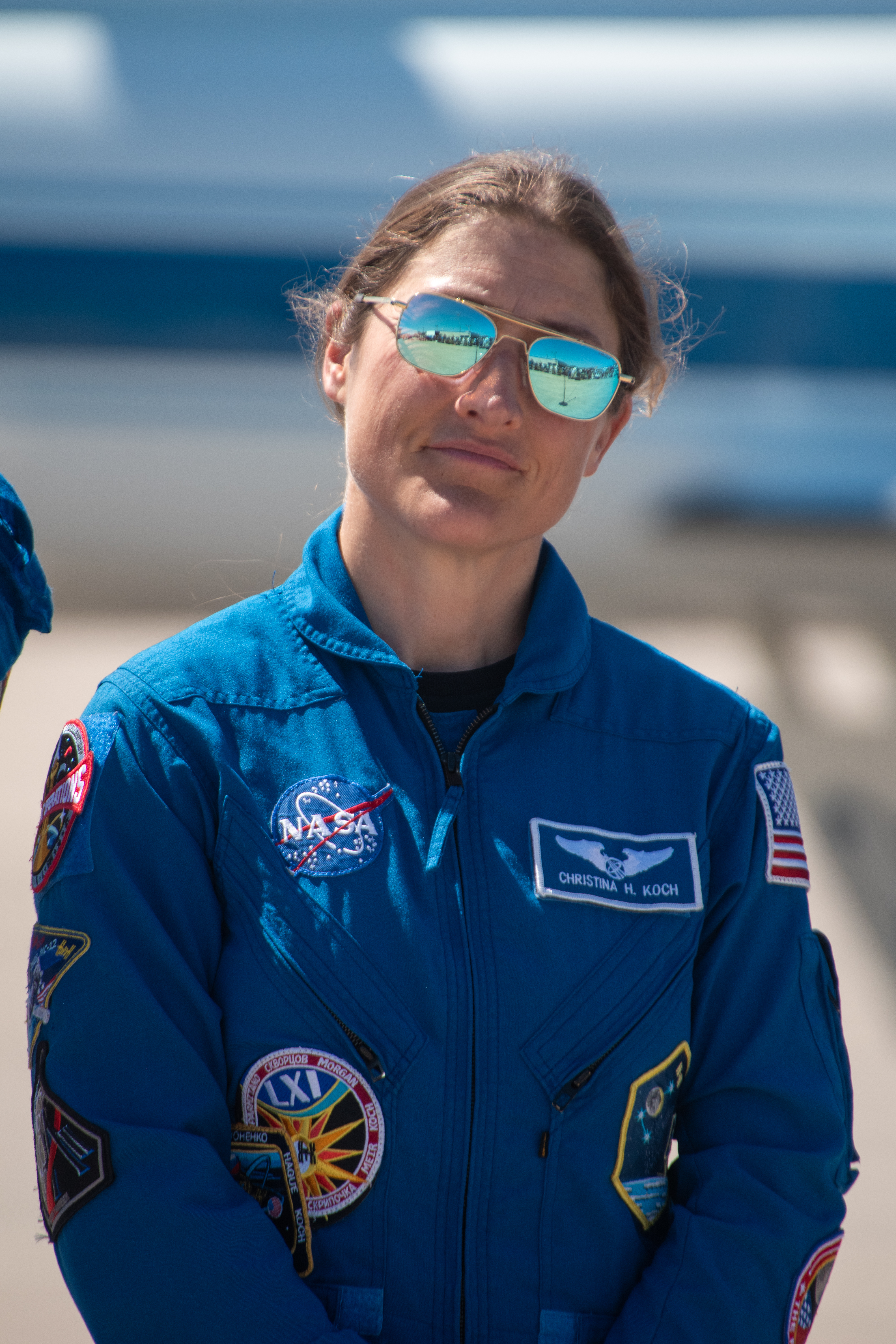 An astronaut in blue jumpsuit stands outside.