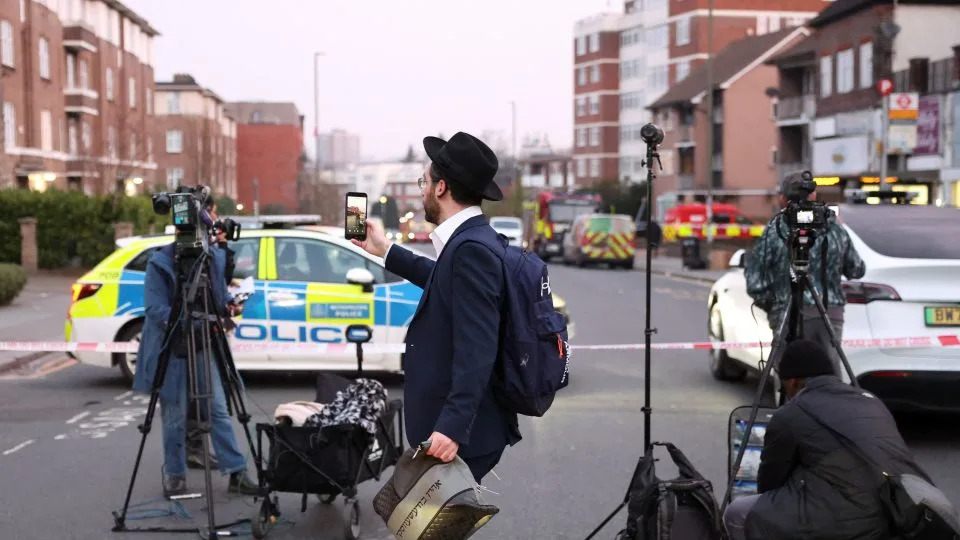 A man records using his mobile phone near the scene of the attack that  police say is being treated as an antisemitic hate crime. - Hannah McKay/Reuters