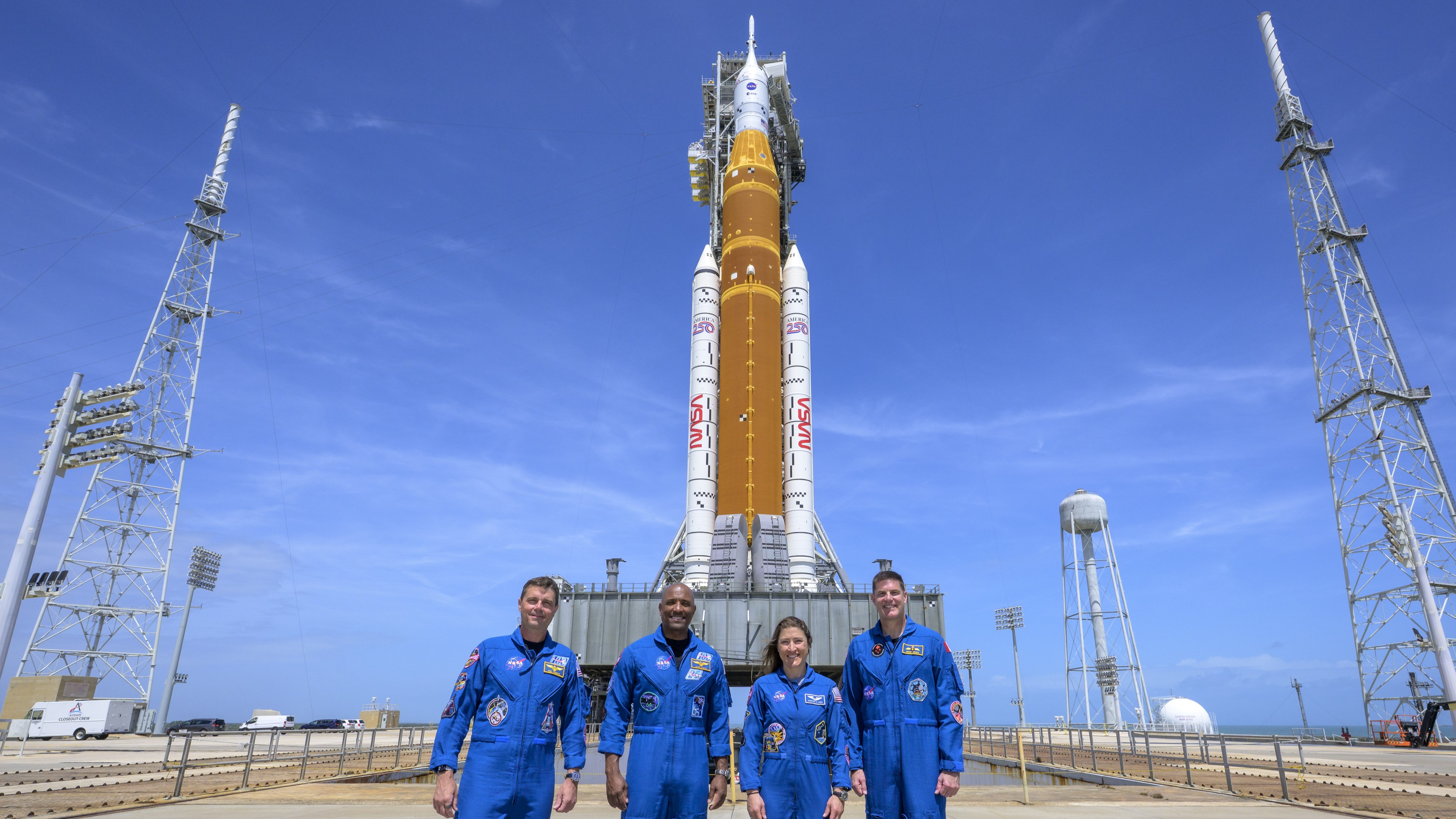 Artemis II's crew stand in front of the rocket.