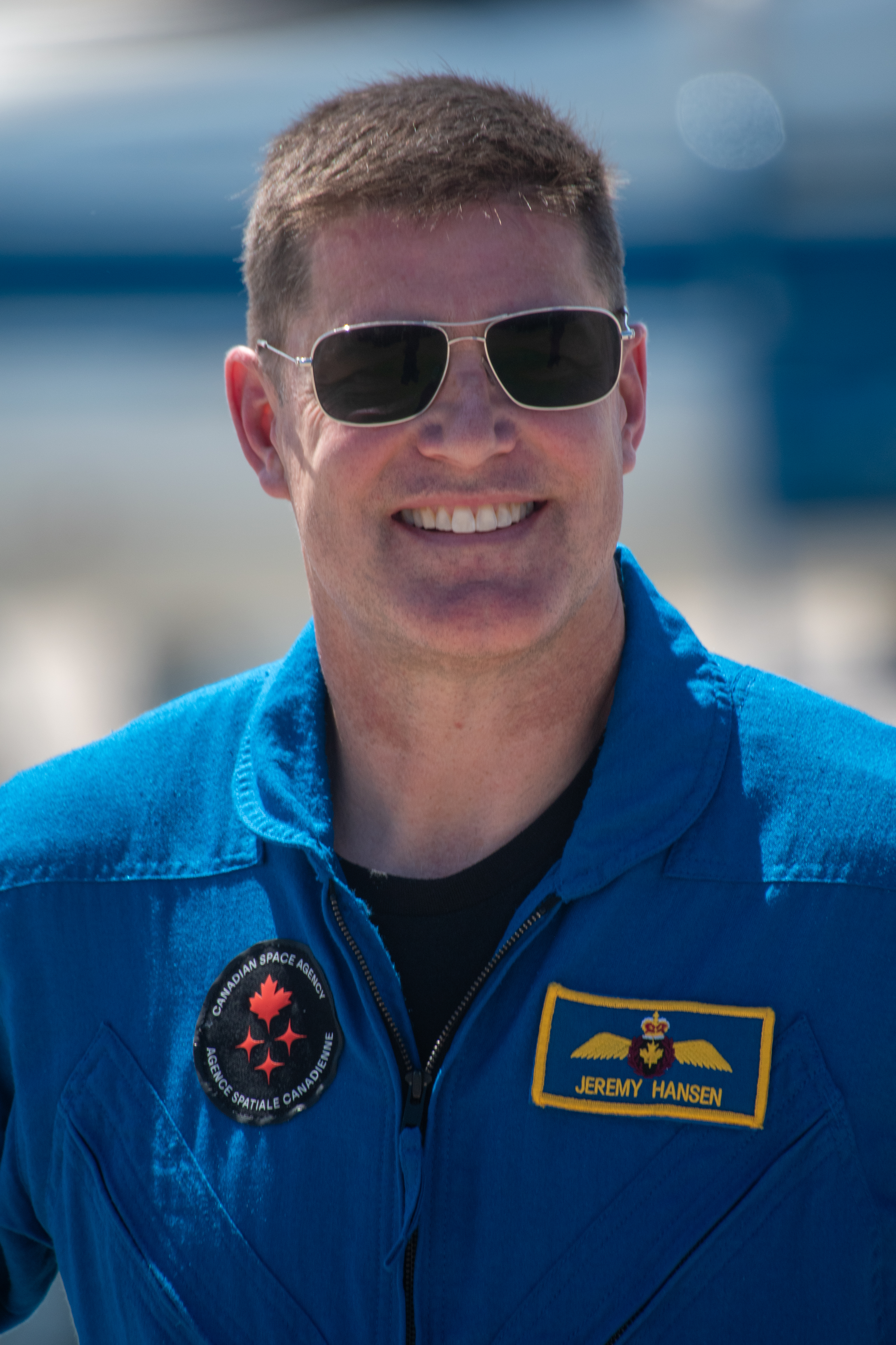 An astronaut in blue jumpsuit stands outside.