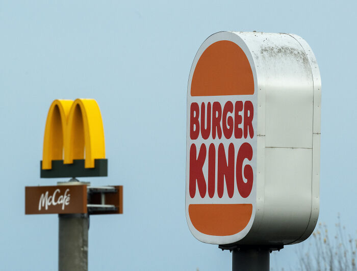 Burger King and McDonald's logos displayed outdoors with focus on Burger King sign against clear sky. Burger King and McDonald's logos displayed outdoors with focus on Burger King sign against clear sky.