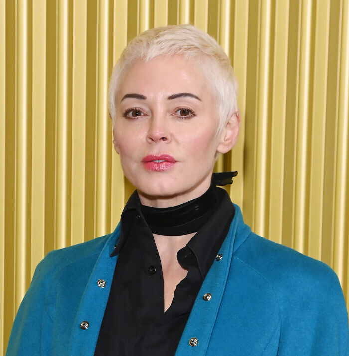 Woman with short blonde hair wearing a black shirt and blue jacket, related to Kaley Cuoco calls out former co-star news.