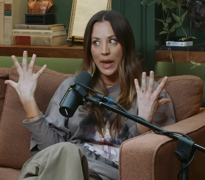 Kaley Cuoco speaking animatedly into a microphone during a podcast interview about former co-star experiences.