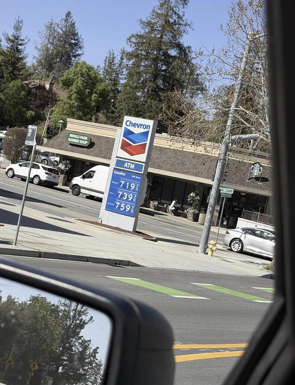 Gas station sign showing prices: Regular $7.19, Plus $7.39, Supreme $7.59. Street view with trees and buildings in the background