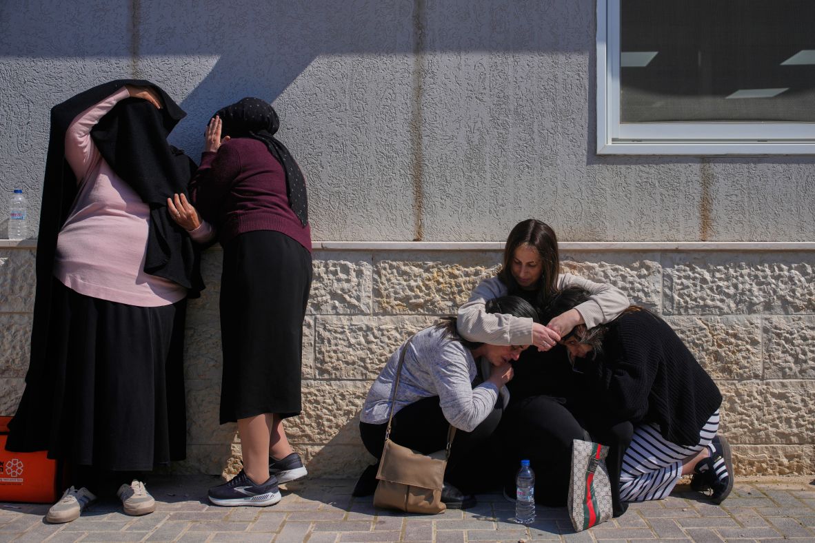 Mourners attending the funeral of Sarah Elimelech and her daughter Ronit take cover Monday while air-raid sirens warn of incoming missiles in Beit Shemesh, Israel.