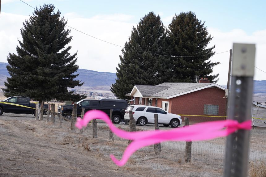 A pink ribbon hangs Thursday on a pole in front of the house where a woman was killed in Lyman, Utah.