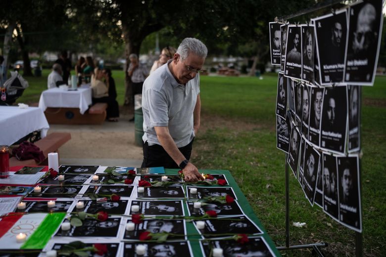 Geev Lameh places a candle by photos said to be of Iranian protesters killed in January, during a community gathering ahead of the Nowruz holiday in the Encino neighborhood of Los Angeles, on March 17.