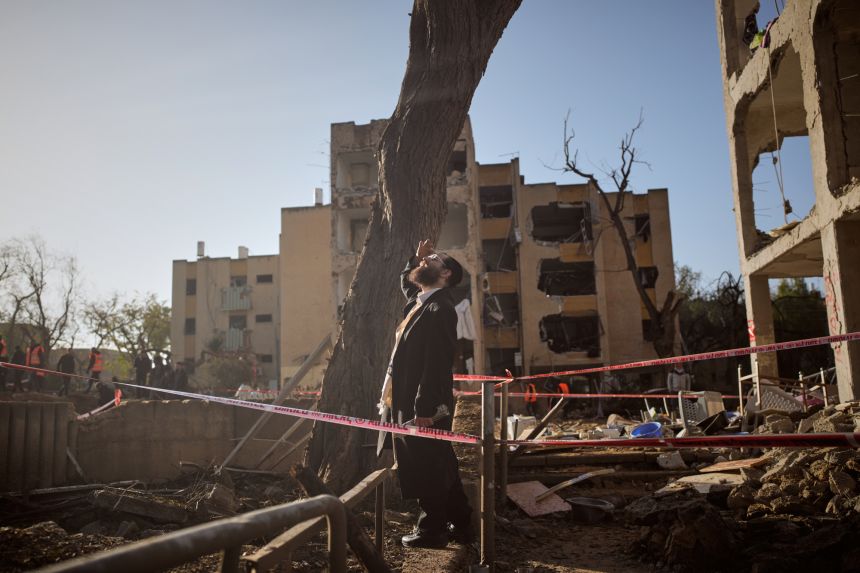 A man looks at residential buildings damaged by an Iranian missile strike in Arad, southern Israel, Sunday, March 22, 2026.