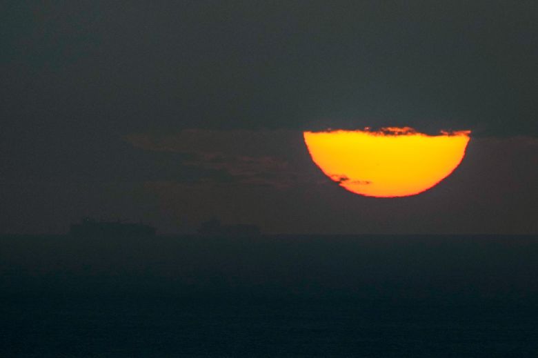 Ships sail through the Arabian Gulf toward the Strait of Hormuz as the sun sets in the United Arab Emirates on Monday.