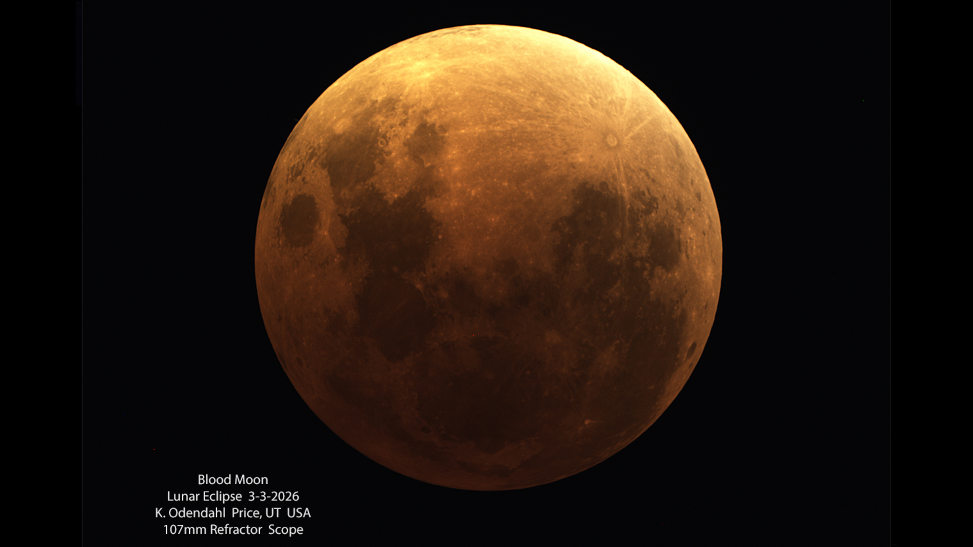 An orange full moon shines against a black sky during the total phase of a lunar eclipse.