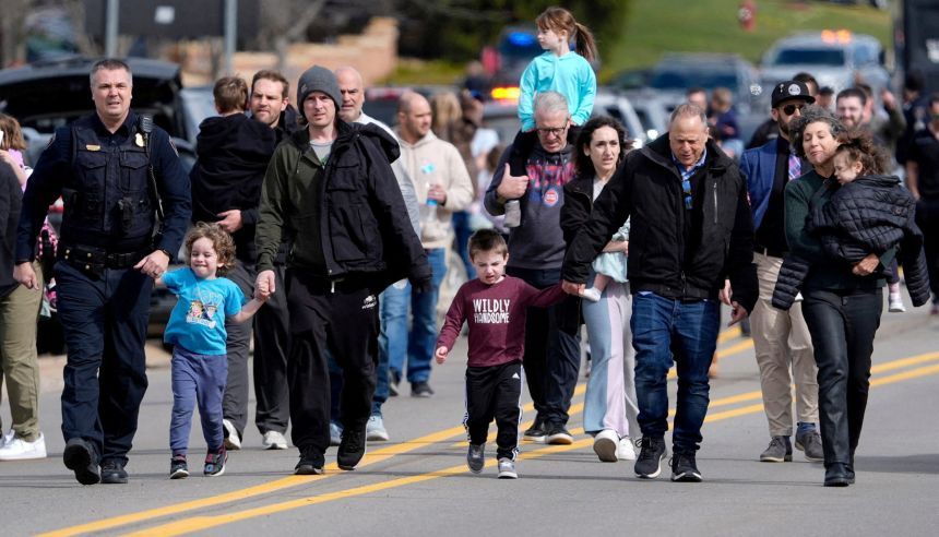 Parents are escorted by police down Walnut Lake Road back to their cars after being reunited with their children Thursday.