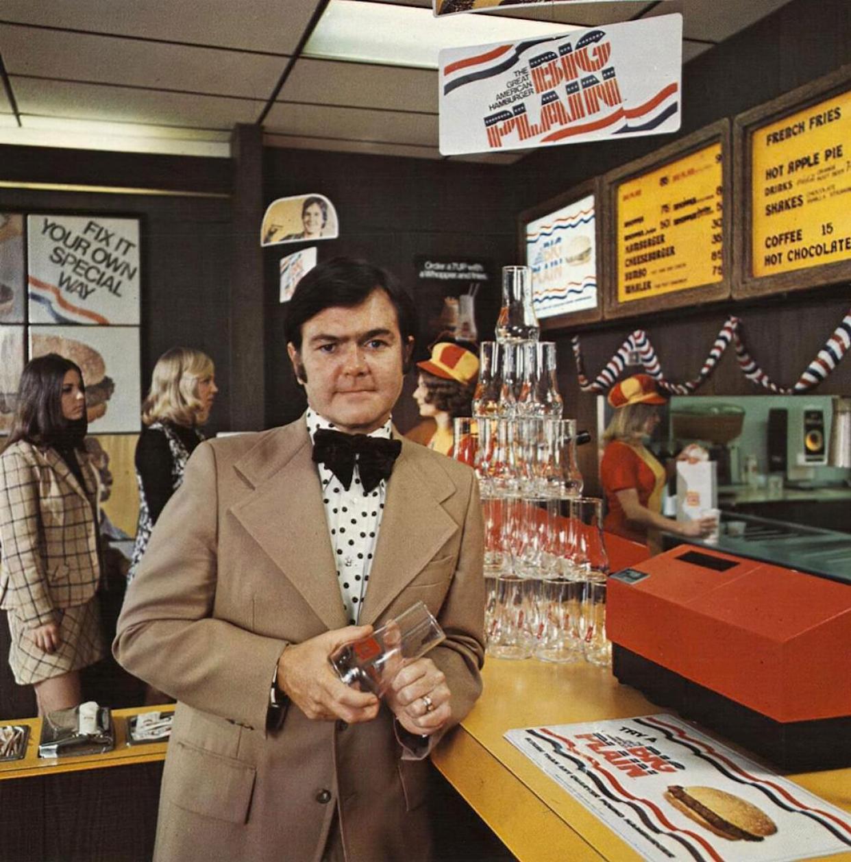 A man in a suit holding a glass inside of a Burger King -