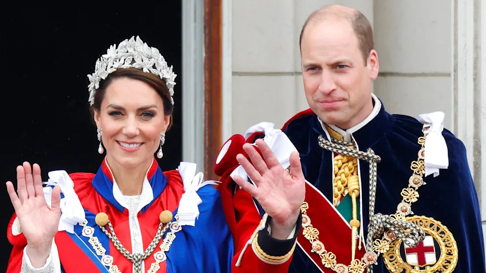 Catherine, Princess of Wales (wearing the Mantle of the Royal Victorian Order) and Prince William, Prince of Wales (wearing the Mantle of the Order of the Garter) wave and watch an RAF flypast from the balcony of Buckingham Palace