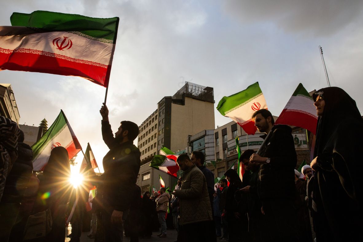 People wave Iranian flags during a rally in Tehran on February 28.