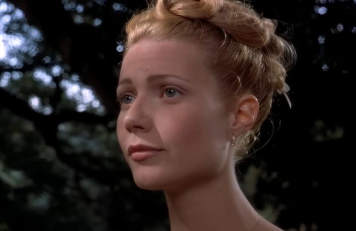 Gwyneth Paltrow with an updo hairstyle, looking thoughtfully into the distance in an outdoor nighttime setting.