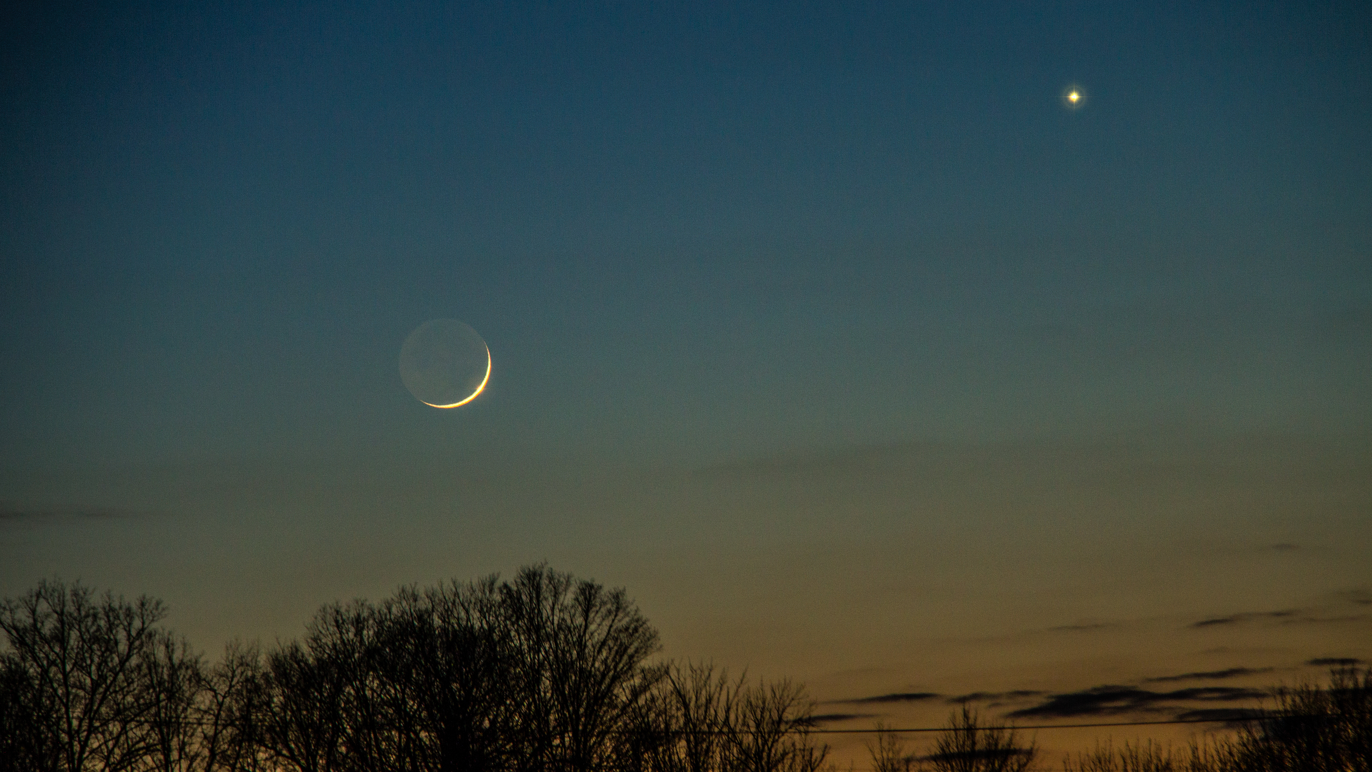 A conjunction of the planets Venus, and Mercury and the moon in a twilight winter sky