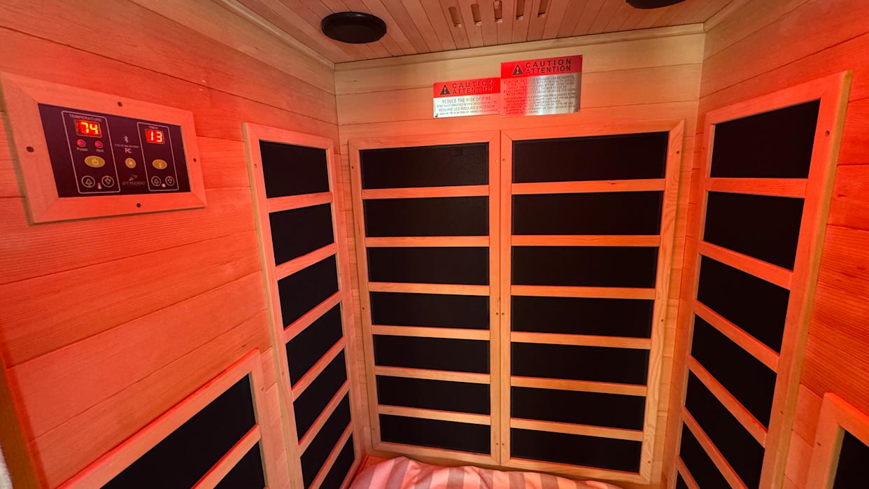 The interior of the sauna features carbon heat panels, a control board, and a bench.