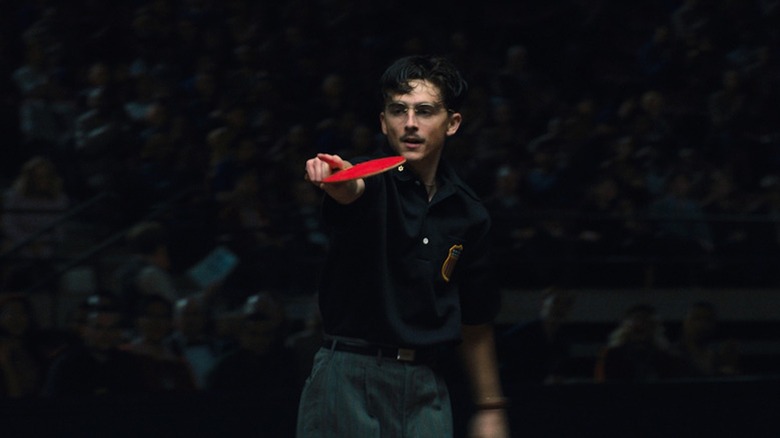 A cocky Timotheé Chalamet holds a table tennis paddle in Marty Supreme