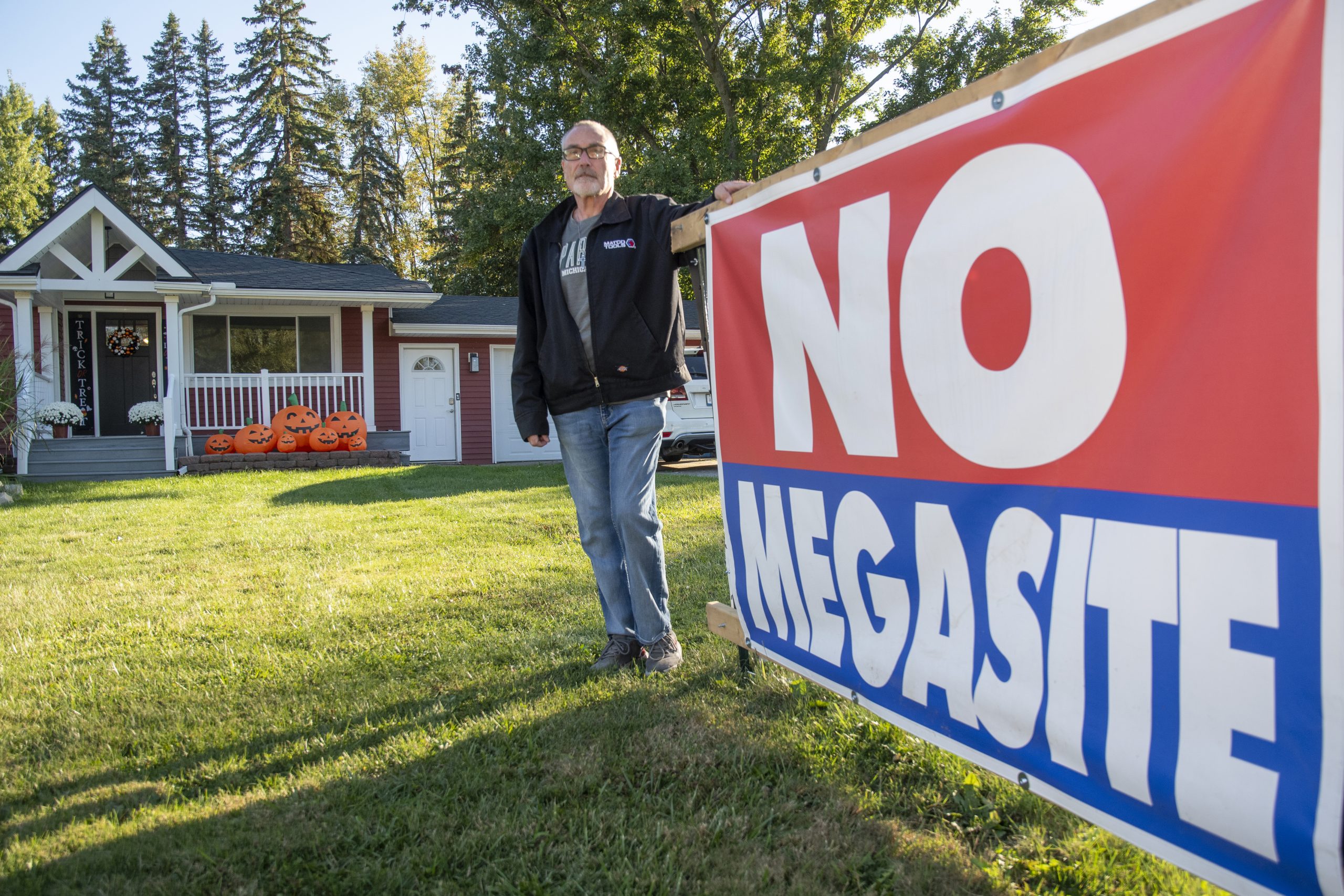 A man standing next to a sign that says "No Megasite." 