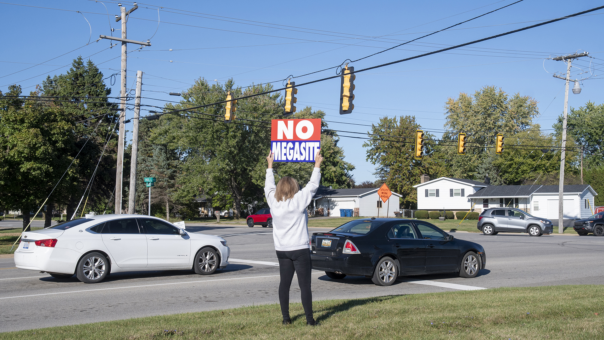 Woman holds anti-megasite sign on the side of the road. 