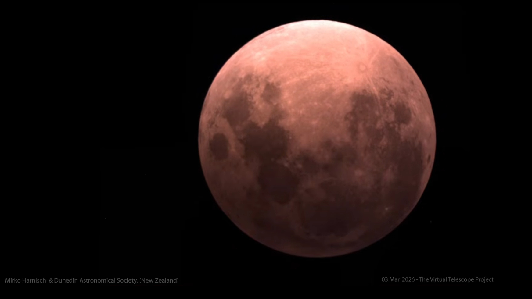 A red full moon is shown against a black sky during a total lunar eclipse.